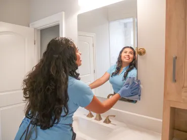 merry maid cleaning a bathroom mirror